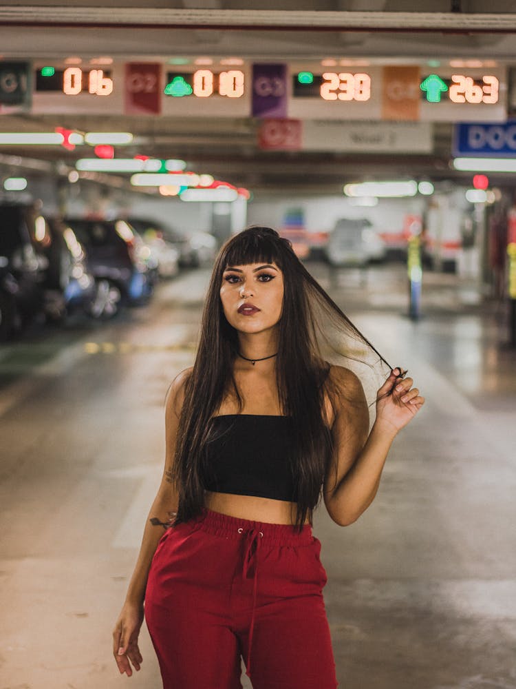 Woman Wearing Red Trousers Posing In Underground Car Park