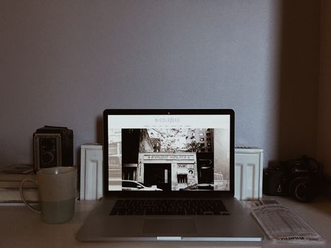 A cozy home office setup with a laptop, vintage camera, and mug, perfect for remote work.