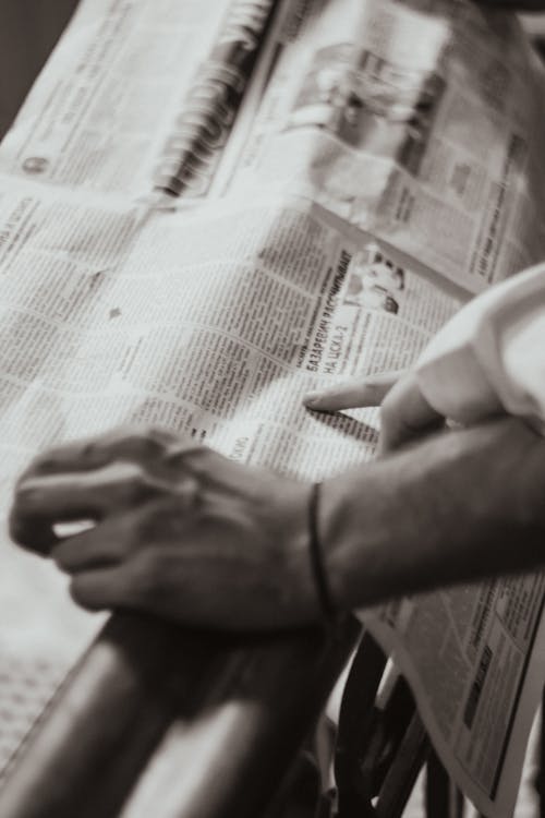 Sepia Toned Image of Two Hands on a Newspaper