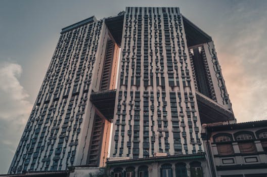 Low-angle view of a modern skyscraper in Singapore at dusk, showcasing urban architectural design.
