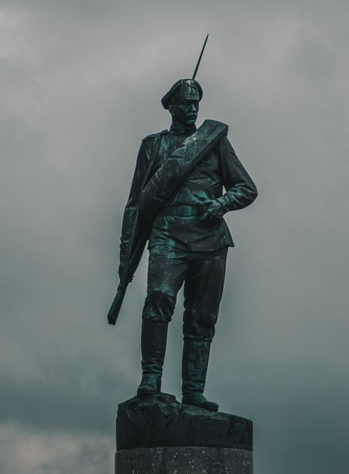 Free Stunning bronze soldier statue with rifle, standing proudly against a moody overcast sky. Stock Photo