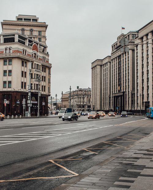 Free A bustling city intersection with vehicles, historic architecture, and a cloudy ambiance. Stock Photo