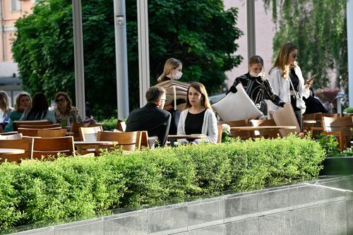 Free A lively outdoor cafe scene with people socializing among green plants under natural daylight. Stock Photo