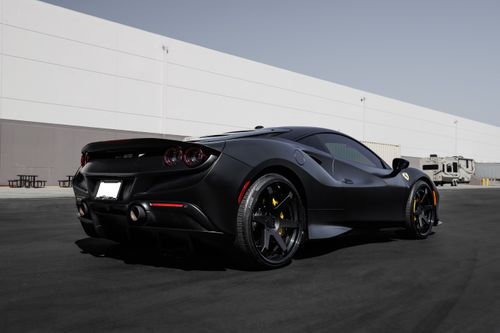 Free Side view of a black luxury sportscar parked outdoors, showcasing its sleek design and modern architecture backdrop. Stock Photo