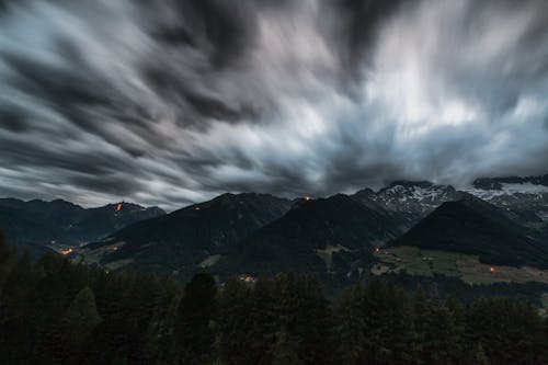 Time Lapse Photography of Pine Trees Near Mountains Under Grey Clouds