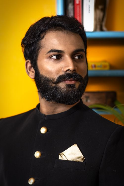 Free Elegant portrait of a stylish bearded man in Indian attire, set indoors with vibrant background. Stock Photo