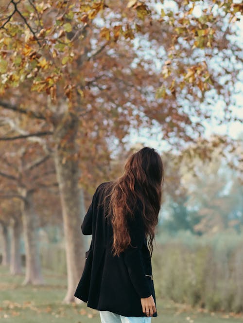 Free Woman in Black Long Sleeve Shirt Standing Near Brown Trees Stock Photo