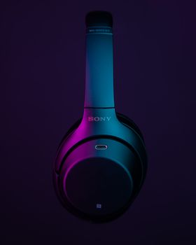 Close-up of sleek wireless headphones with a vibrant neon glow, emphasizing cutting-edge technology.