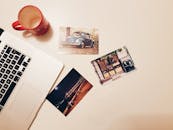 办公桌上摆放着笔记本电脑、咖啡杯和打印照片，整体环境干净、极简