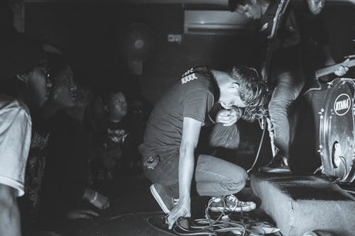 Black and White Shot of a Vocalist Crouching on Stage