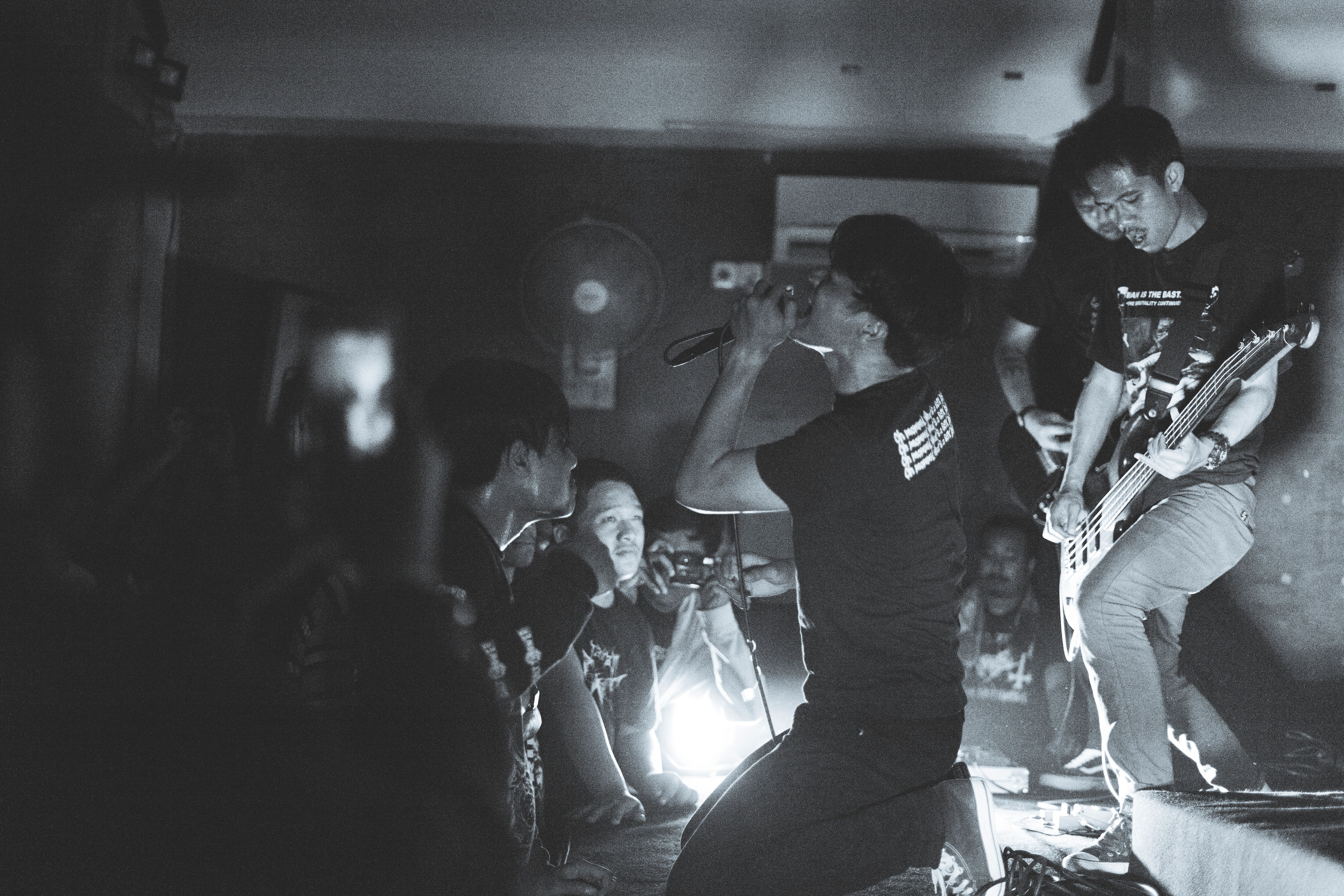 Black and white photo of a live rock performance with a singer and guitarist captivating an audience.