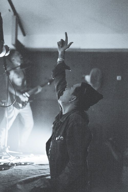 Free Captivating black and white photo of a concertgoer raising a hand passionately during a live music performance. Stock Photo