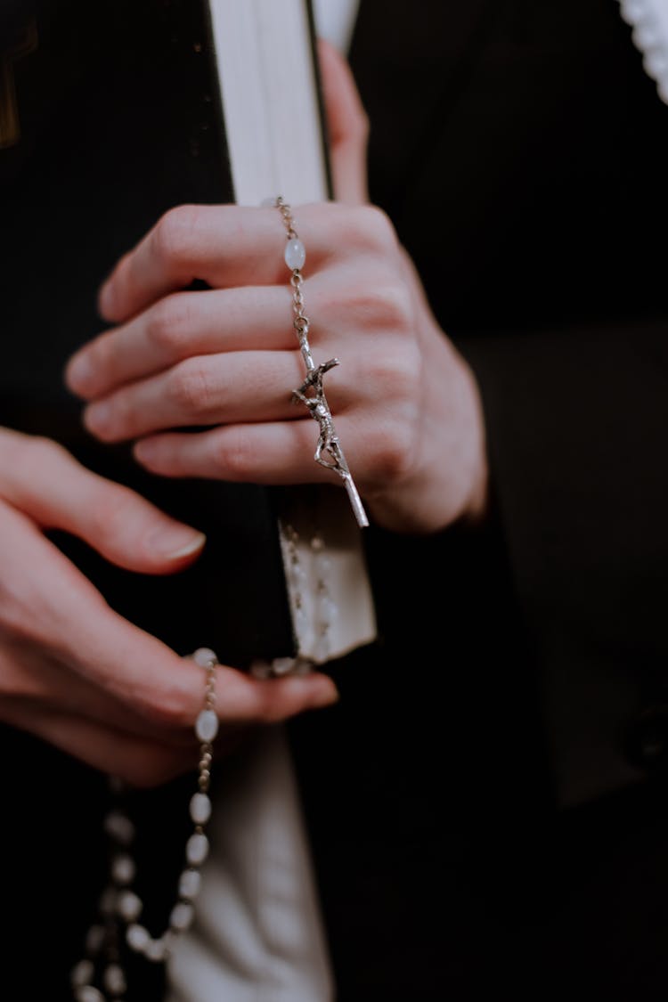 Woman In Black Robe Holding A Book And A Rosary With A Cross