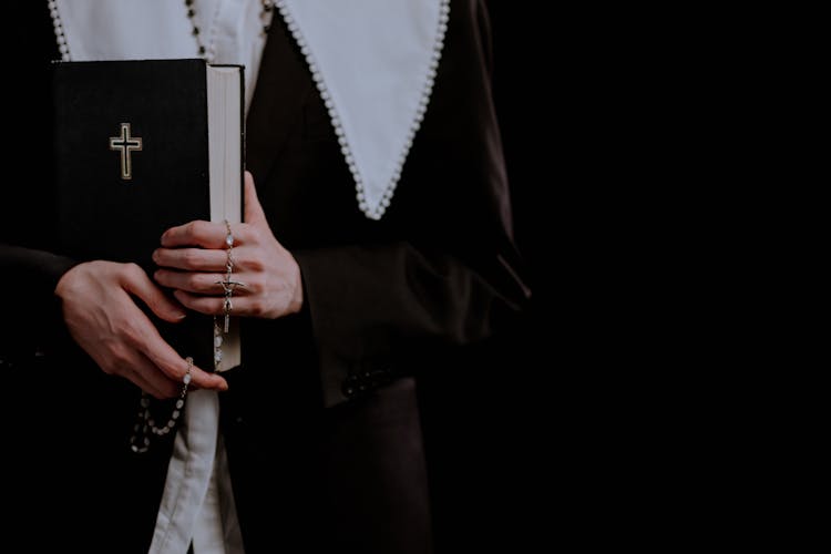 Person Holding A Rosary And A Bible