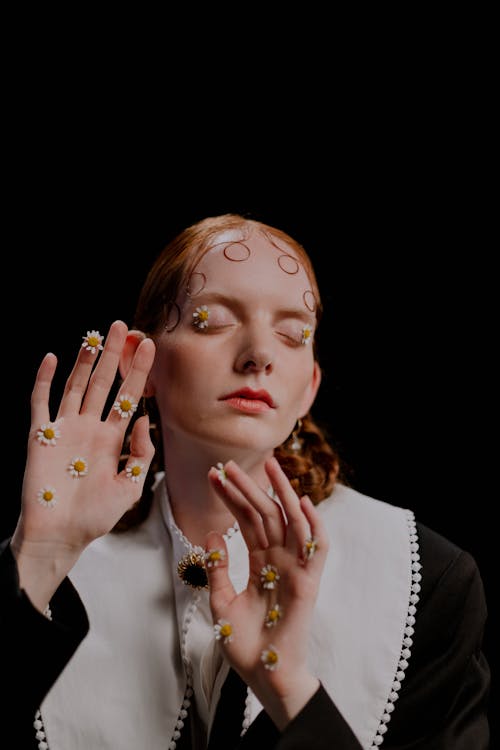 A Woman in Black Long Sleeves with White Flowers on Her Palm Posing at the Camera while Eyes are Closed