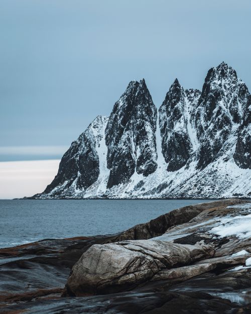 Free Stunning snowcapped peaks in Norway's Nurlann region with moody sky and ocean view, perfect for nature lovers. Stock Photo