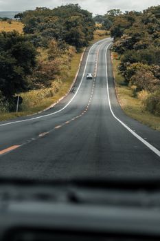 A solitary car travels along a winding road through lush countryside, evoking a sense of adventure.