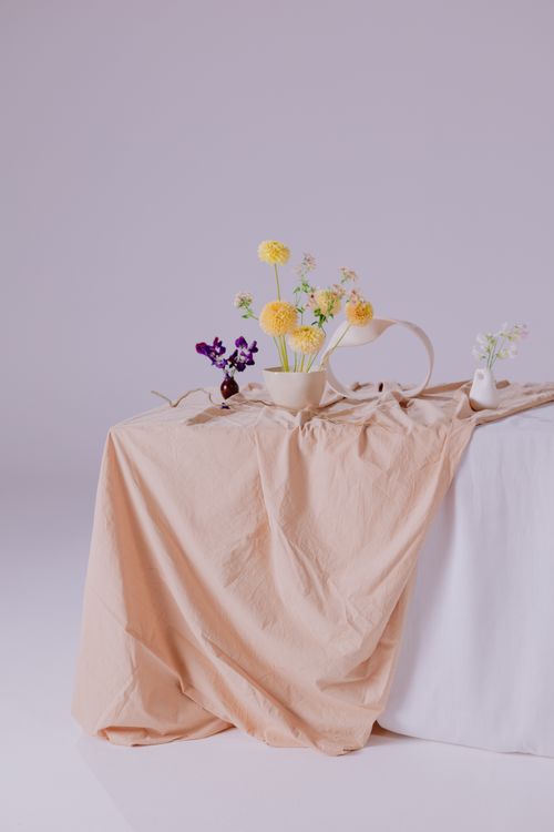 Free Elegant minimalist still life with flowers in a ceramic vase on a draped tablecloth. Stock Photo