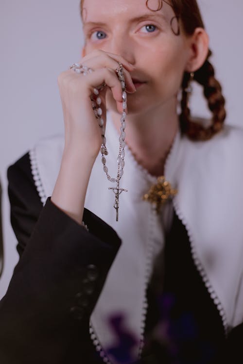Free A Woman in Black and White Long Sleeve Blouse Holding a Rosary Stock Photo