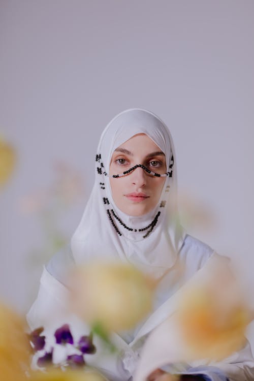 Woman in White Hijab With a String of Beads on Her Face