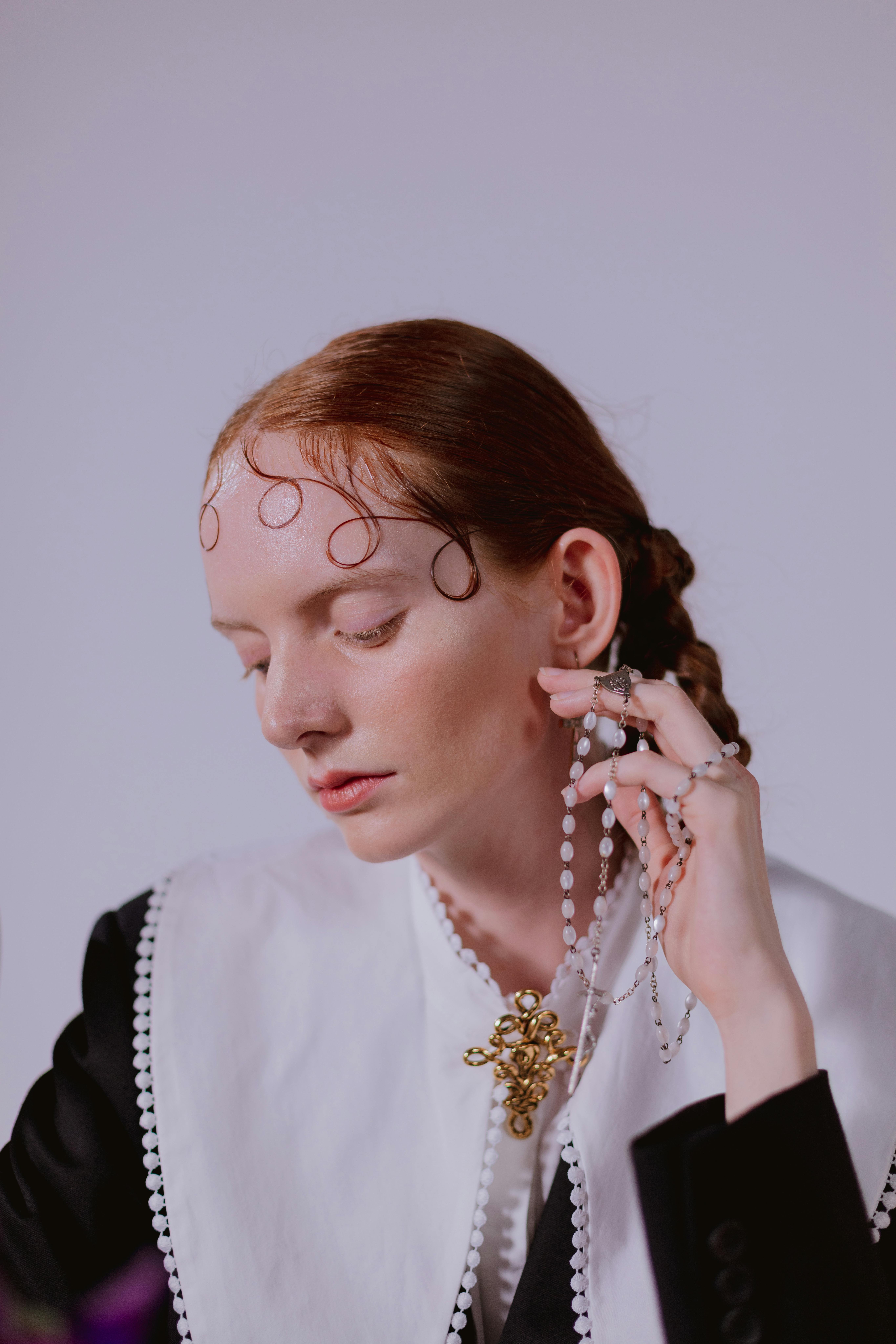 穿着时尚服装的深思熟虑的女人拿着念珠，象征着时尚与灵性的结合