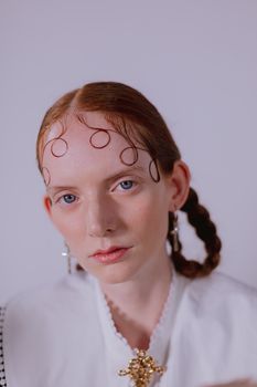 Close-up portrait of a fashionable woman with unique hairstyle and accessories in a studio setting.