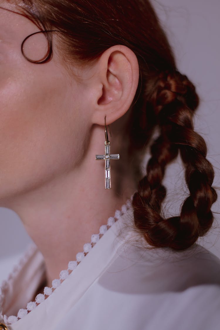 A Person Wearing A Crucifix Earring