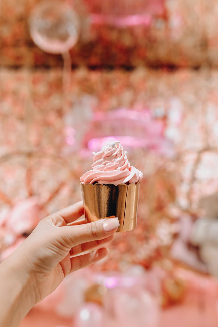 Womans Hand Holding Cupcake With Pink Cream 