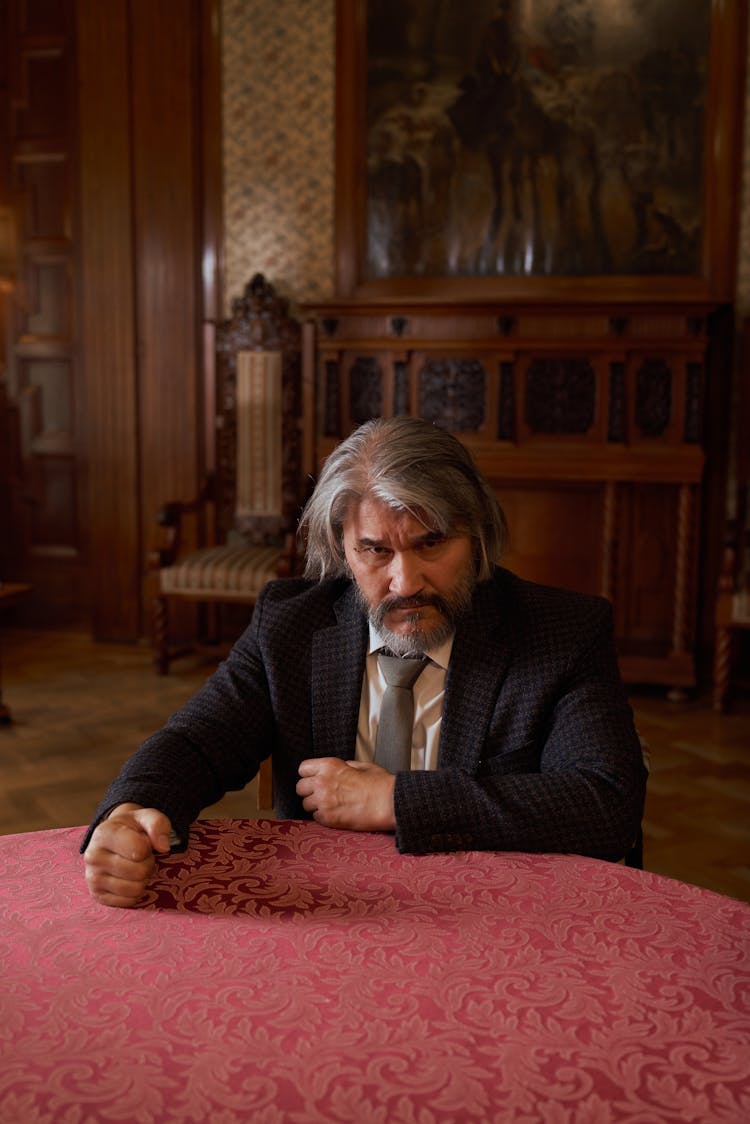 Bearded Senior Man With Gray Hair Holding His Fist On Table