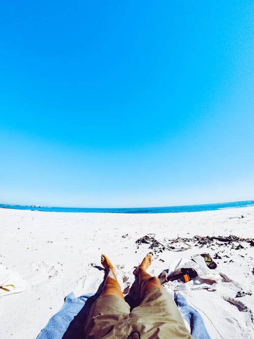 무료 회색 반바지 해변에서 하얀 모래에 누워있는 남자 스톡 사진