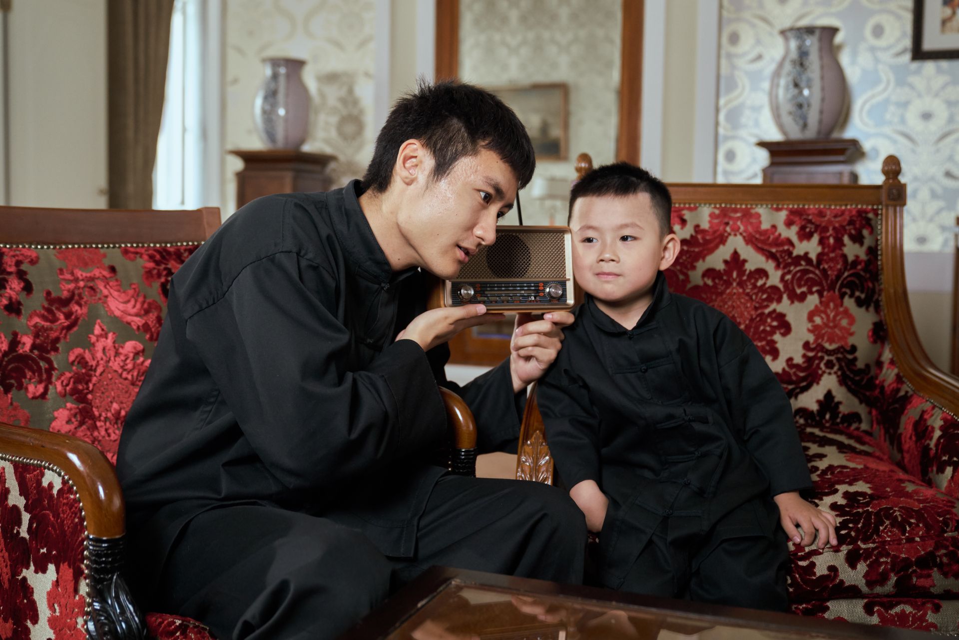 A father and son share a moment listening to a vintage radio in a retro-style living room.