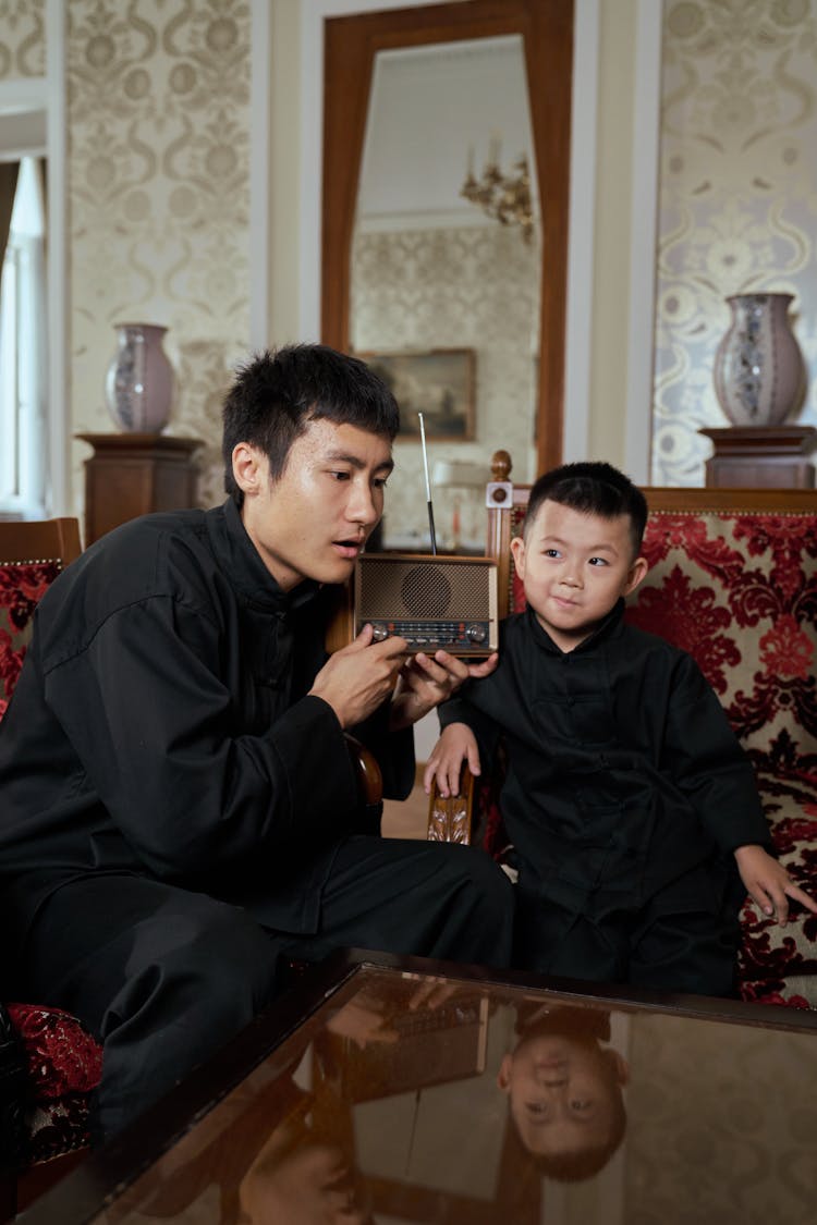 Father And Son Listening To Radio Broadcast With Interest