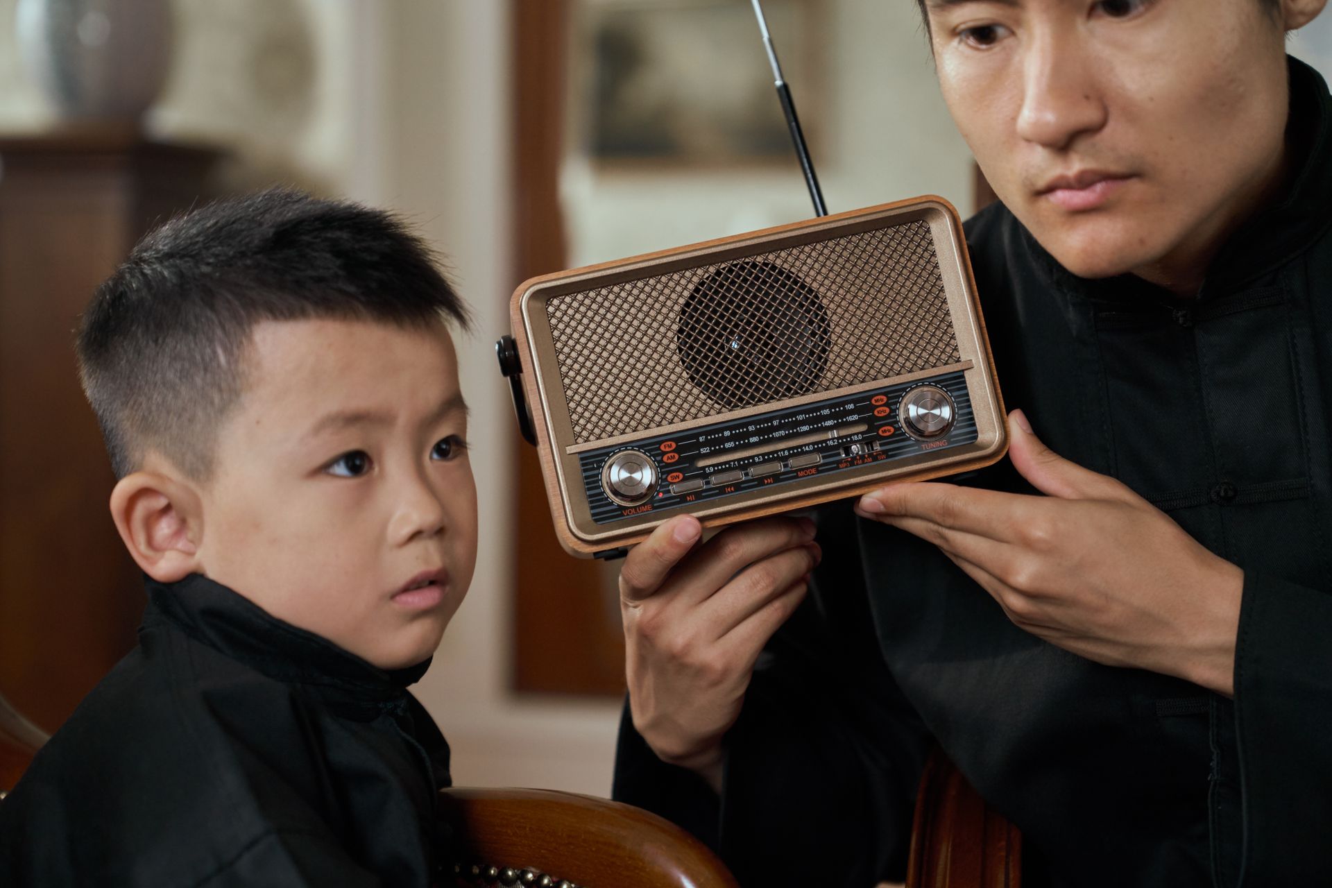 Father and Son Listening to Radio with Attention