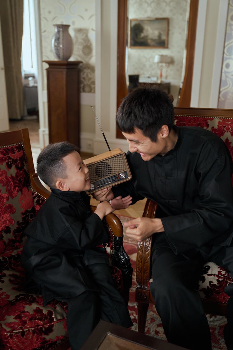 Father And Son Playing At Home When Listening To Transistor Radio