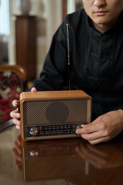 Unrecognizable Man Turning Knob of Retro Transistor Radio