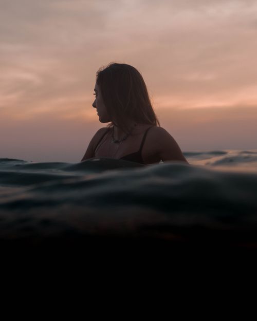 Free Woman enjoying the ocean during a serene sunset in Rio de Janeiro, Brazil. Stock Photo