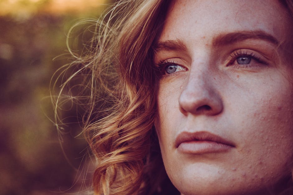 Close-up portrait of a young woman with curly hair and blue eyes, exuding calmness.