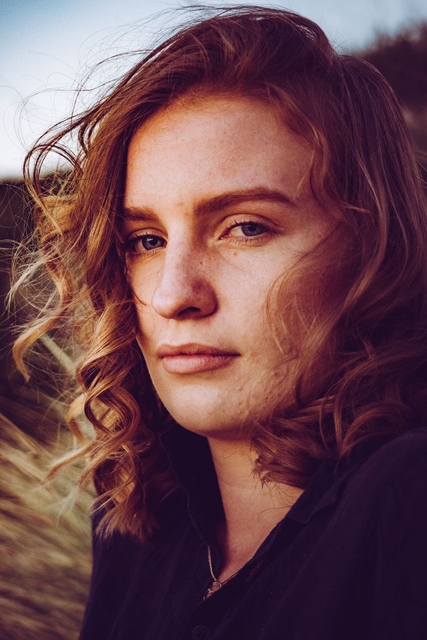 Close-up portrait of a woman with red hair during golden hour, showcasing natural beauty and outdoor lighting.. pexels, close