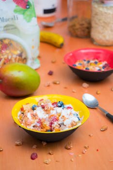 Vibrant breakfast bowl with muesli, yogurt, and fresh fruits on a wooden table.