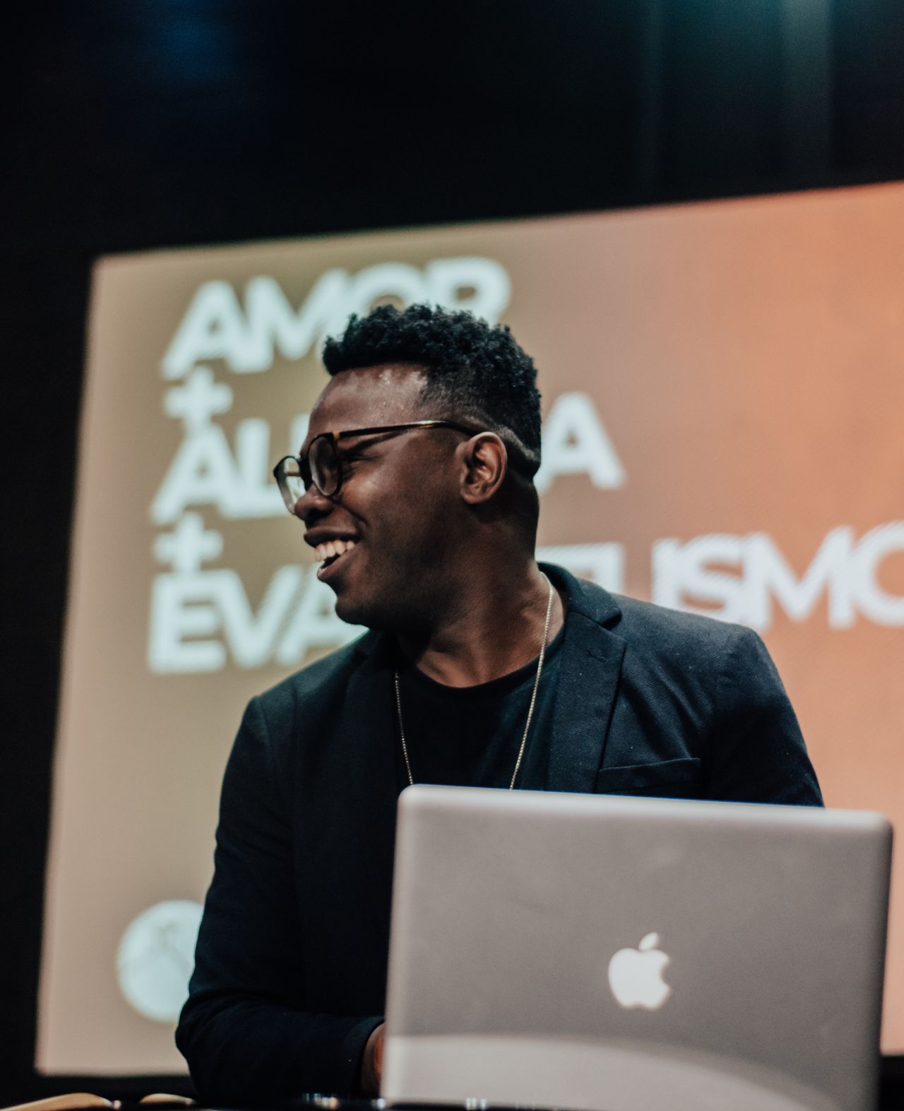Smiling man presenting with a laptop, engaging audience in Rio, Brazil.
