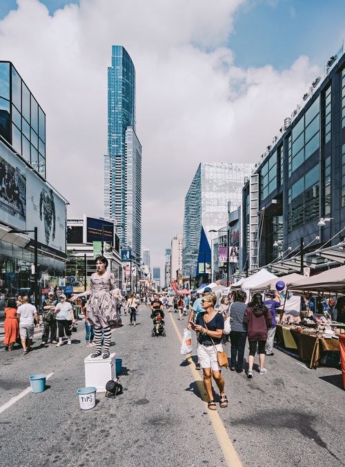 Free Vibrant street scene in Toronto with performers, people, and skyscrapers. Stock Photo