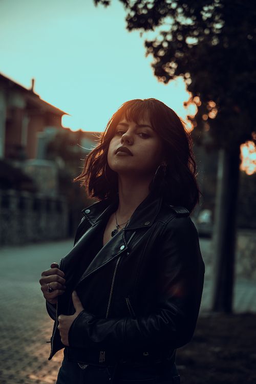 Free Fashionable woman in a black leather jacket posing outdoors during twilight, creating a moody atmosphere. Stock Photo