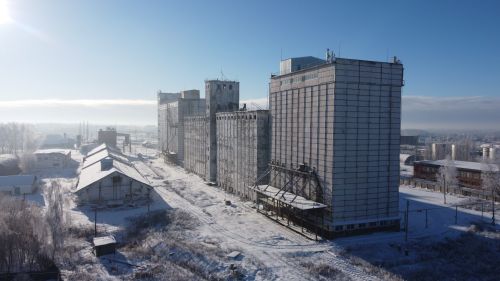 Free Aerial view of a snow-covered industrial building under a clear blue sky in winter. Stock Photo