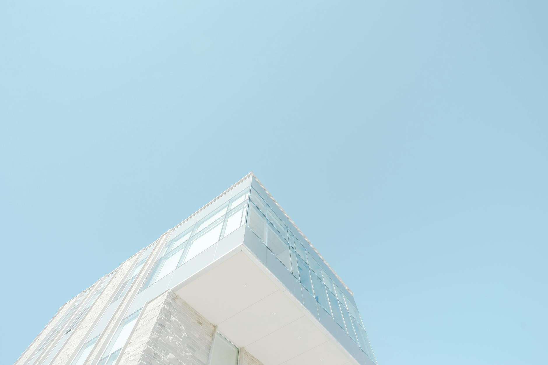 A low-angle shot of a modern building with a glass facade against a bright blue sky in London, Canada.
