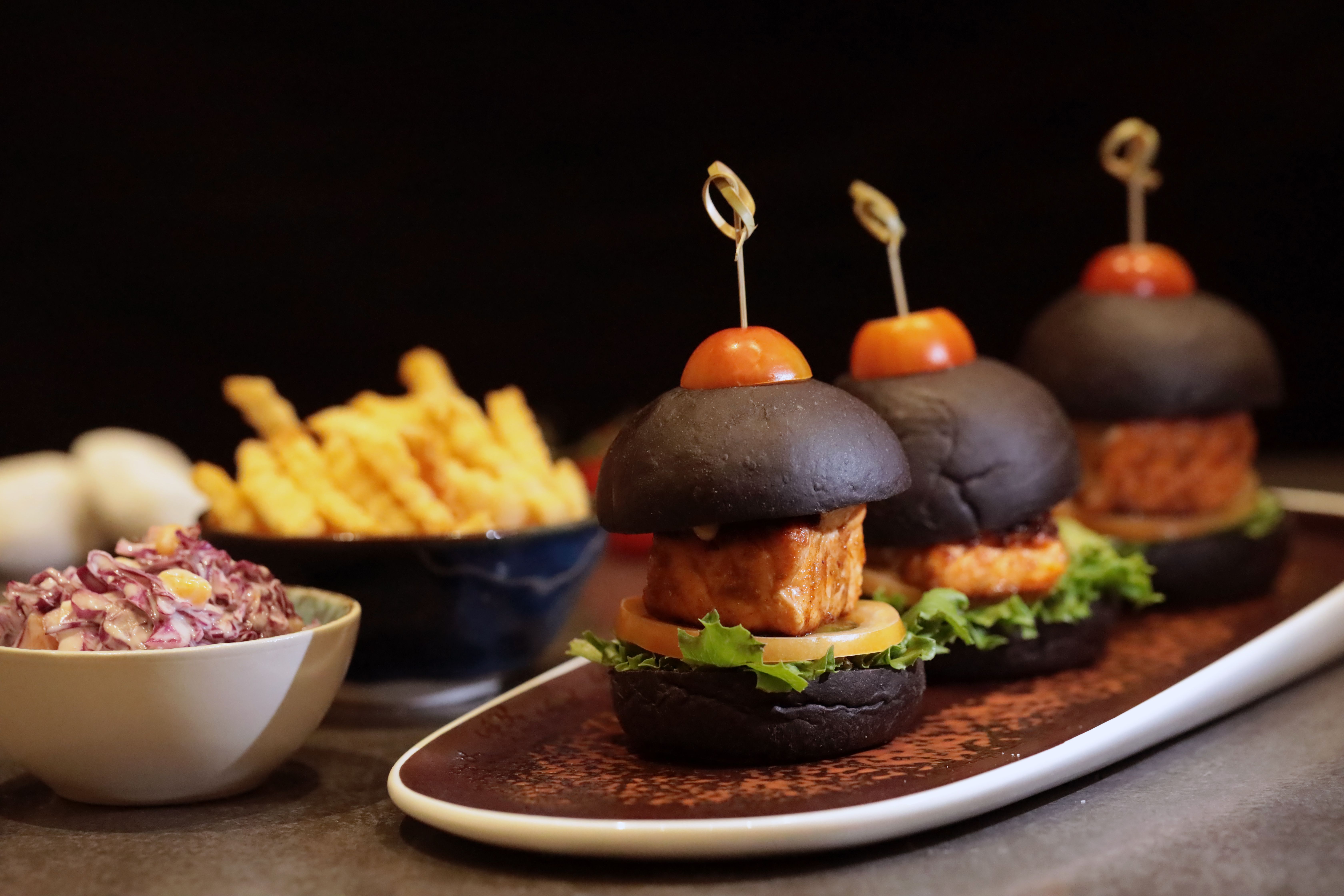 A battered fish burger with tartar sauce on a bun