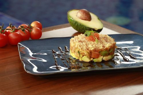 Free Delicious avocado and salmon tartare served on a stylish black tray with cherry tomatoes. Stock Photo
