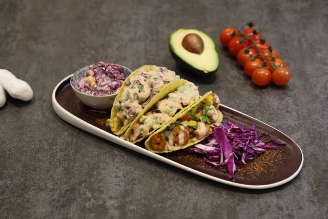 Appetizing shrimp tacos served with fresh avocado and a side of cabbage slaw.