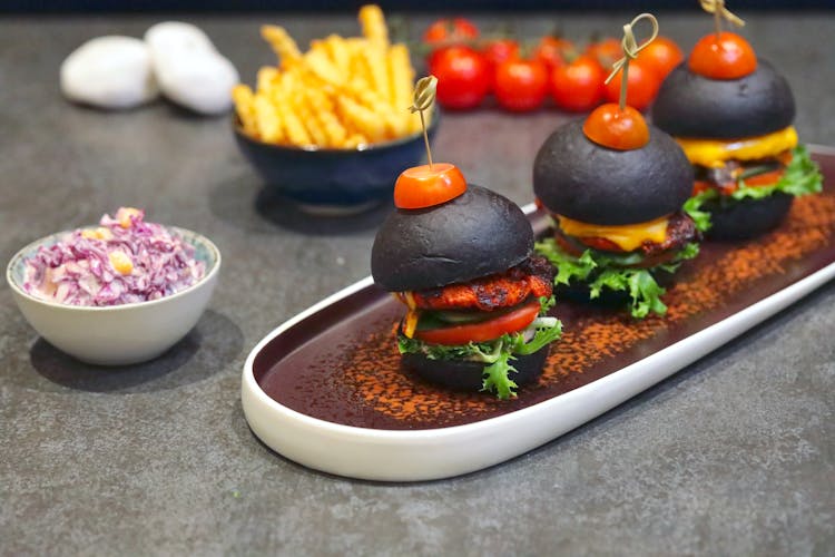 Black Cheese Burgers With Slices Of Tomatoes Pinned With Sticks