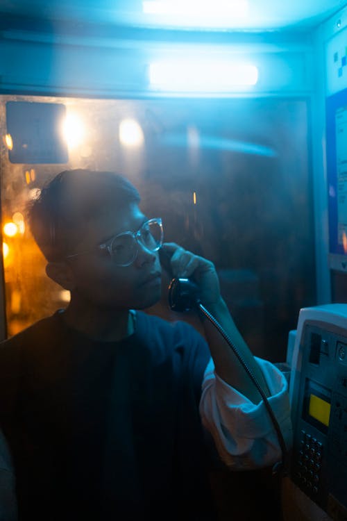 Man in Glasses Talking on Phone in Booth