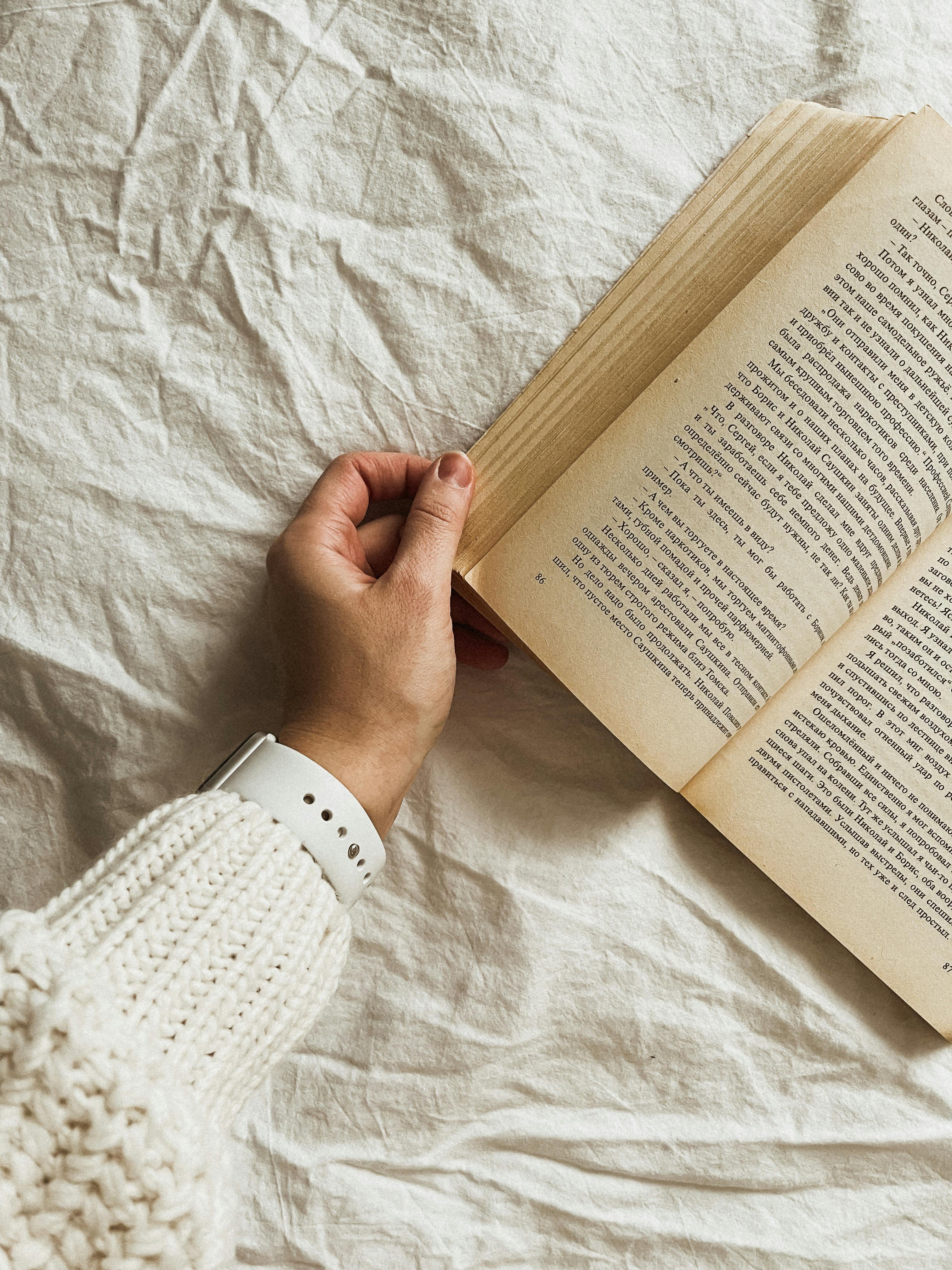 hand of a person holding a book on white cloth